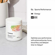White plastic jar of Thorne Advanced Pre-Workout powder with colorful watercolor logo on countertop.