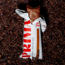 PRIMA Ancestral Protein Bar with white and red wrapper on chocolate cacao nibs background.