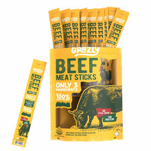 A yellow Grazly Beef Meat Sticks bag with a grazing bull illustration, with individually wrapped sticks rising from the top and one beside it.