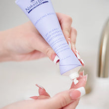 Lavender tube of Naked Bee SPF 30 moisturizer being squeezed onto a person's hand, showing white cream product.
