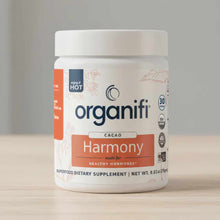 White container of Organifi Harmony cacao-flavored superfood dietary supplement powder, 9.52 oz, with orange and navy label d