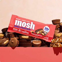Red MOSH High Protein bar with creatine in peanut butter cup flavor surrounded by chocolate candies.