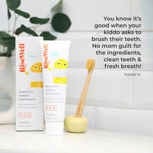 Two tubes of RiseWell kids mineral toothpaste with yellow fish design, wooden toothbrush in yellow holder, and green plant.