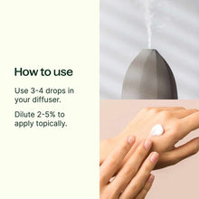 Gray ultrasonic diffuser with steam and hands receiving white lotion with usage instructions for essential oil.