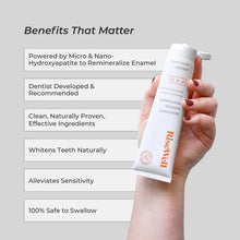 Hand holding white RiseWell PRO Mineral Toothpaste tube with orange text and product benefits listed on gray background.