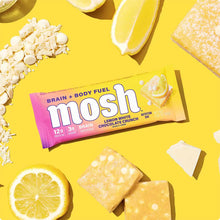 MOSH Lemon White Chocolate Crunch protein bar with 12g protein, surrounded by lemon slices and oats on yellow background.