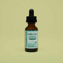 Brown glass bottle with black dropper cap labeled "Charlotte's Web Daily Care CBD Extract Oil" on pale yellow background.