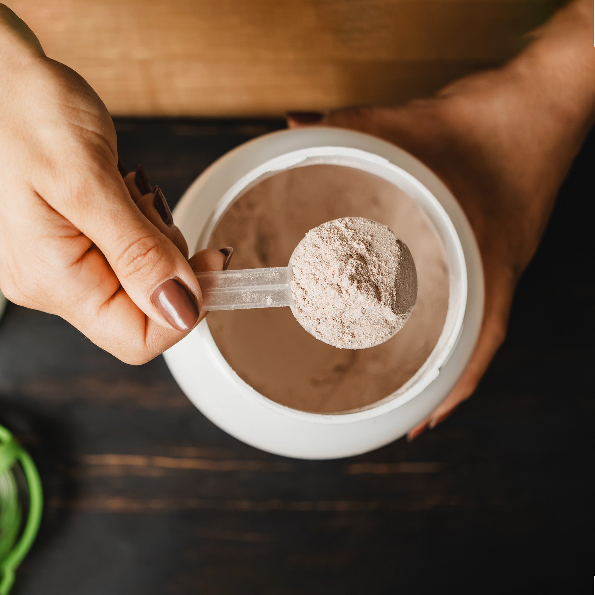 A women scooping protein powder out of a jug
