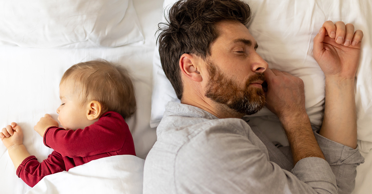 A father and child both asleep in bed facing opposite directions