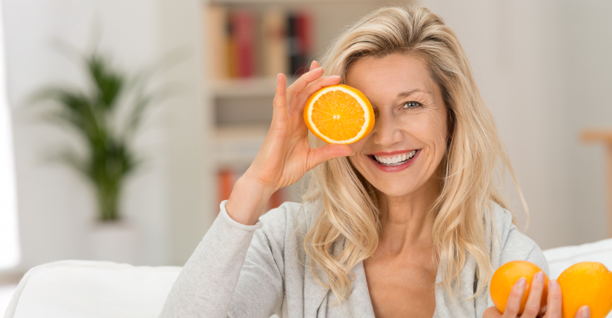 A women holding half of an orange up to her eye