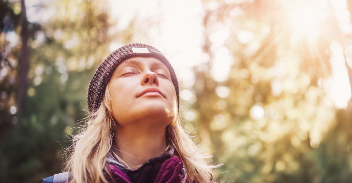 A young woman outdoors with her eyes closed enjoying the fresh air