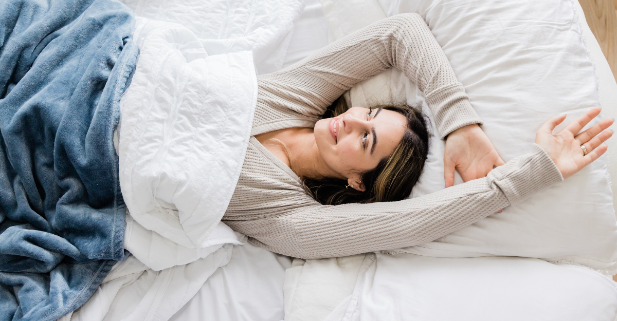 A woman smiling comfortable in bed with her arms spread out