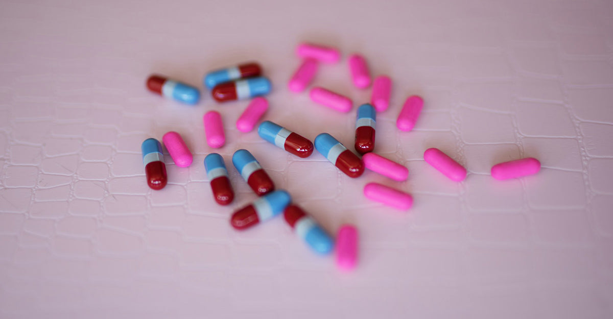 A variety of iron pills on a light pink background