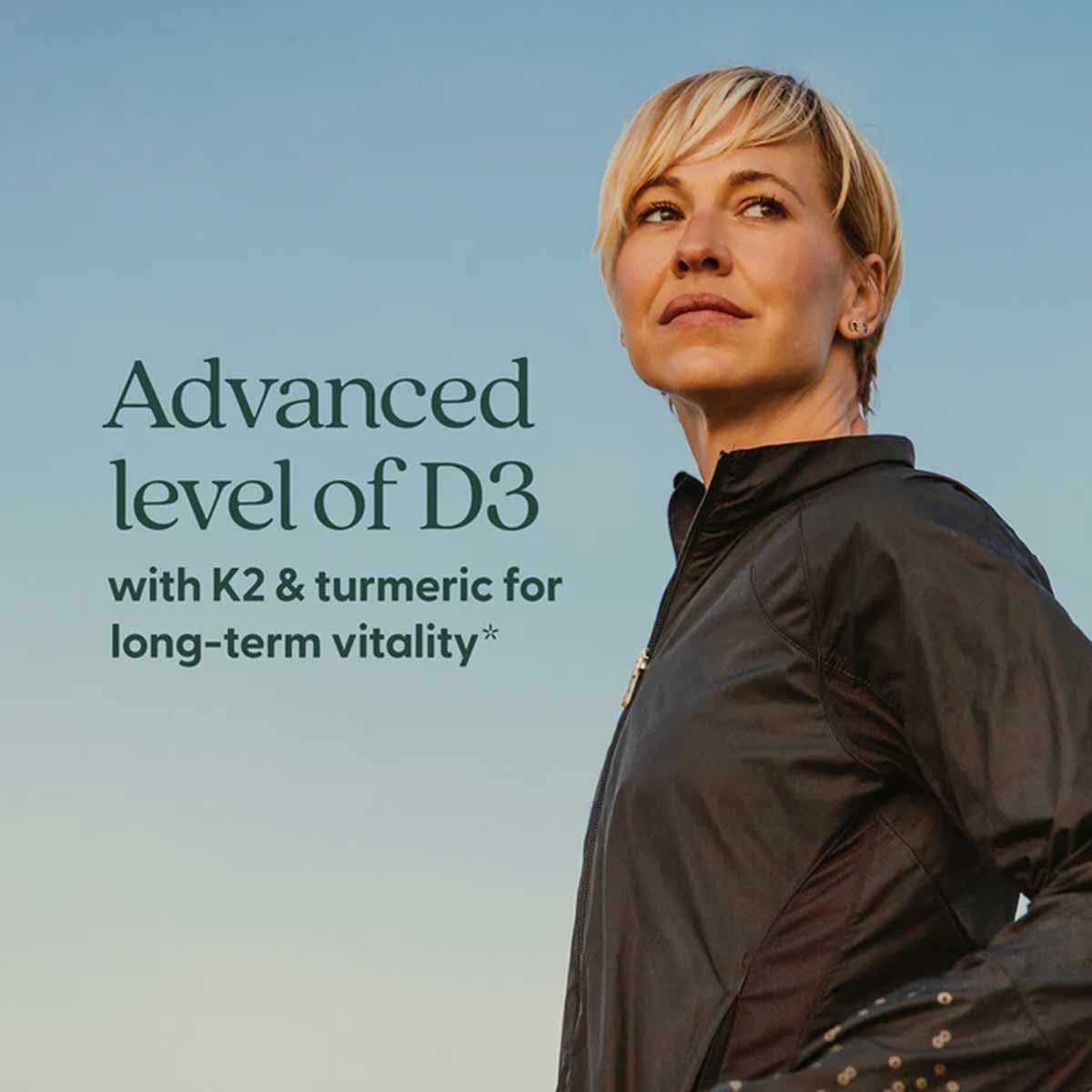 Woman wearing black jacket against blue sky with text describing D3, K2, and turmeric supplement benefits.