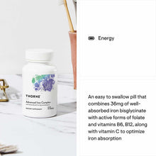 White bottle of Thorne Advanced Iron Complex dietary supplement with colorful logo on marble surface.