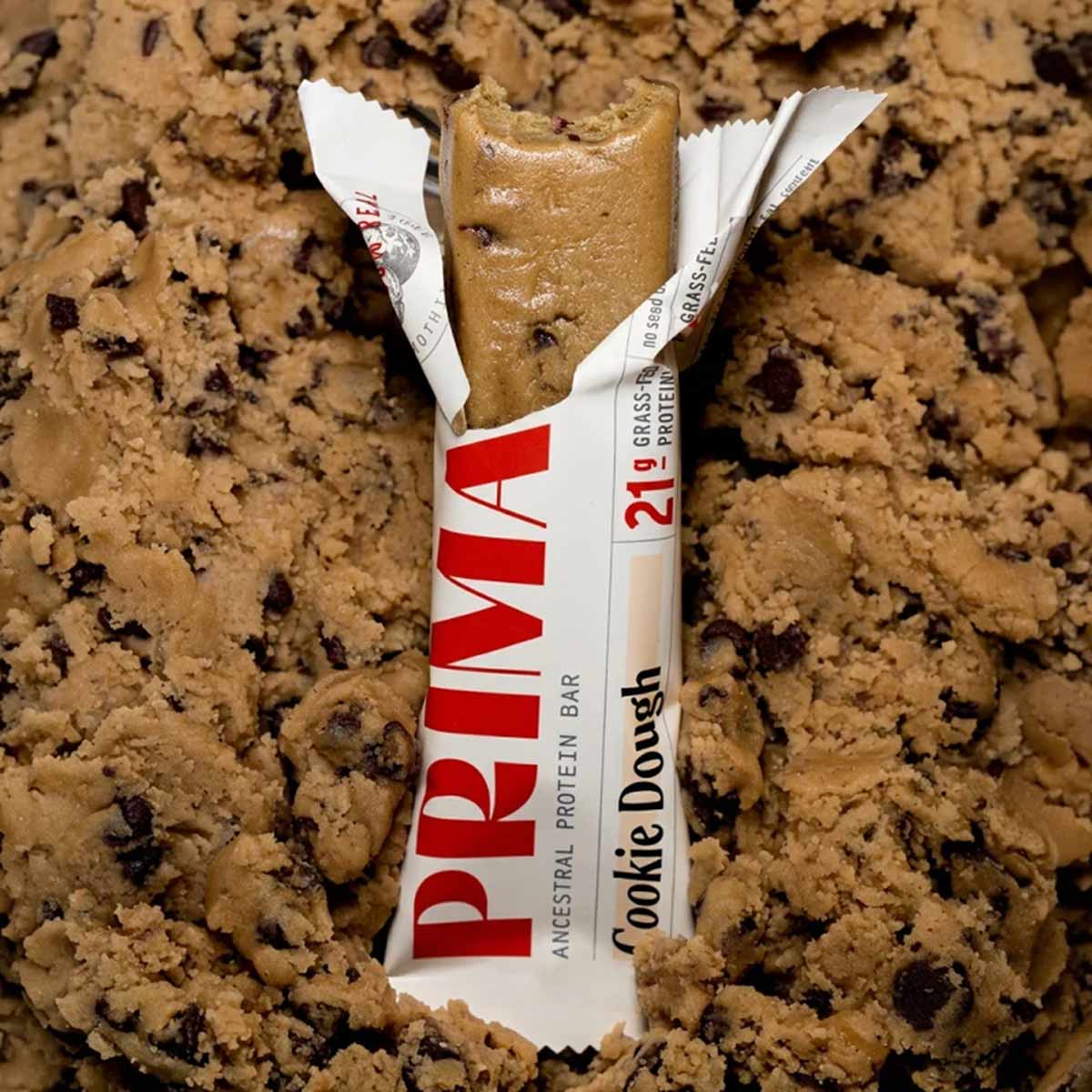 PRIMA Ancestral Protein Bar in Cookie Dough flavor, partially unwrapped, displaying 20g protein content on packaging.