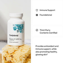 White bottle of Thorne Vitamin C 1,000 mg supplement with blue map graphic and white cap, displayed next to yellow sponge.