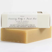 A tan bar of soap sits beneath a boxed bar with a cream label reading Milk Cleansing Body and Facial Bar, unscented.