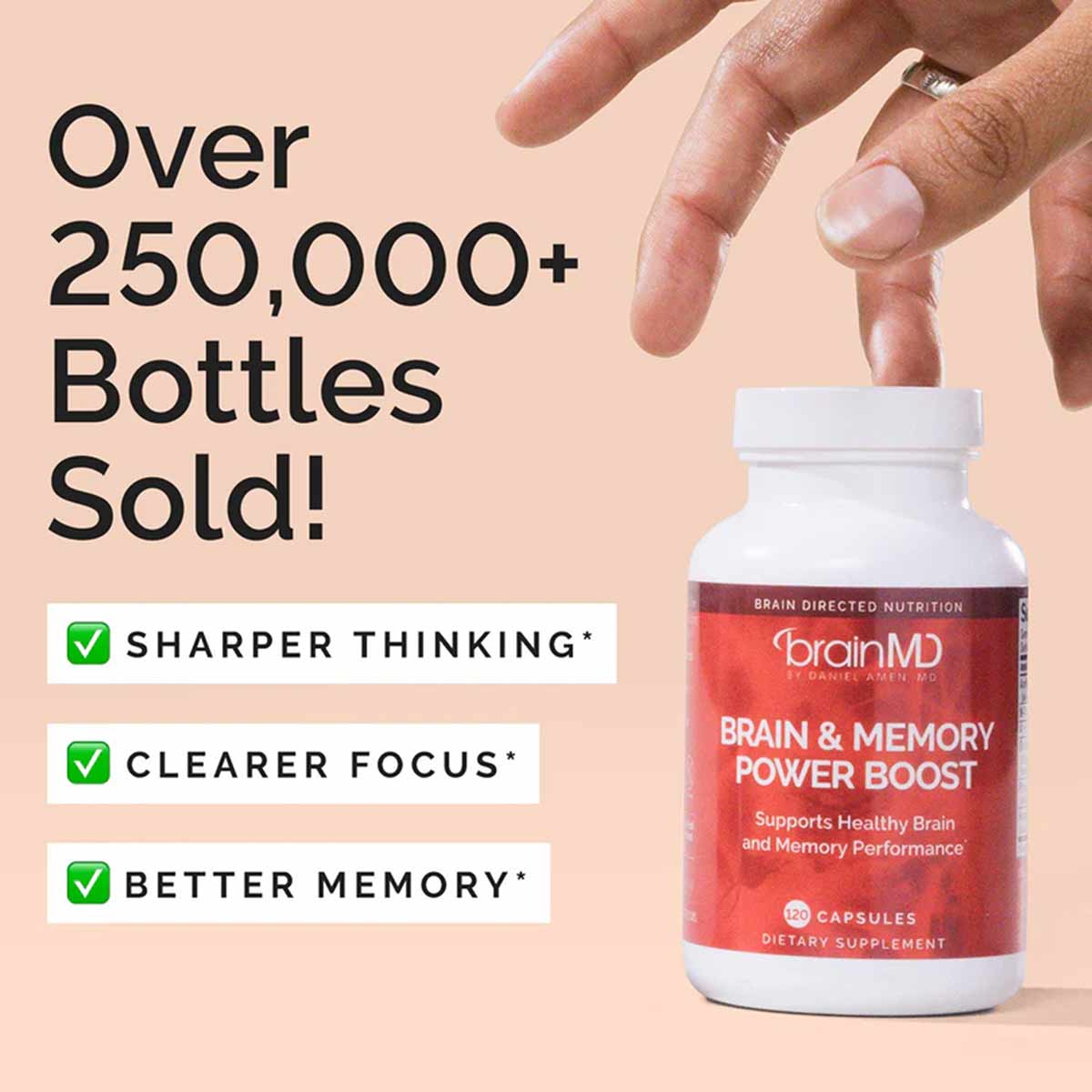 White BrainMD Brain & Memory Power Boost bottle with red label held in hand against peach background.