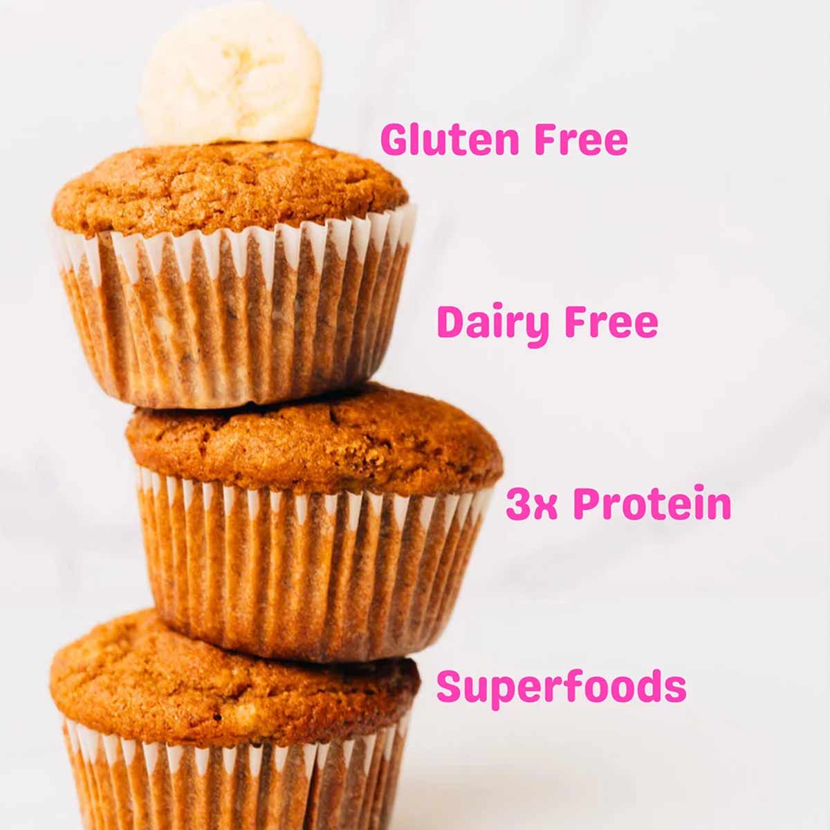 Three banana muffins in paper liners are stacked with a banana slice on top, beside pink text listing dietary claims.