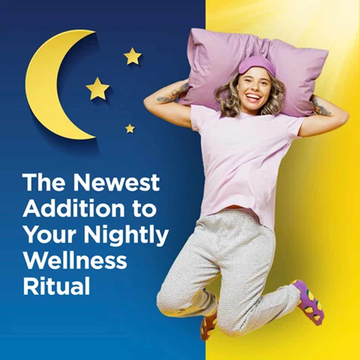 Woman in pink pillow hat and white shirt jumping against blue and yellow background with moon and stars graphic.