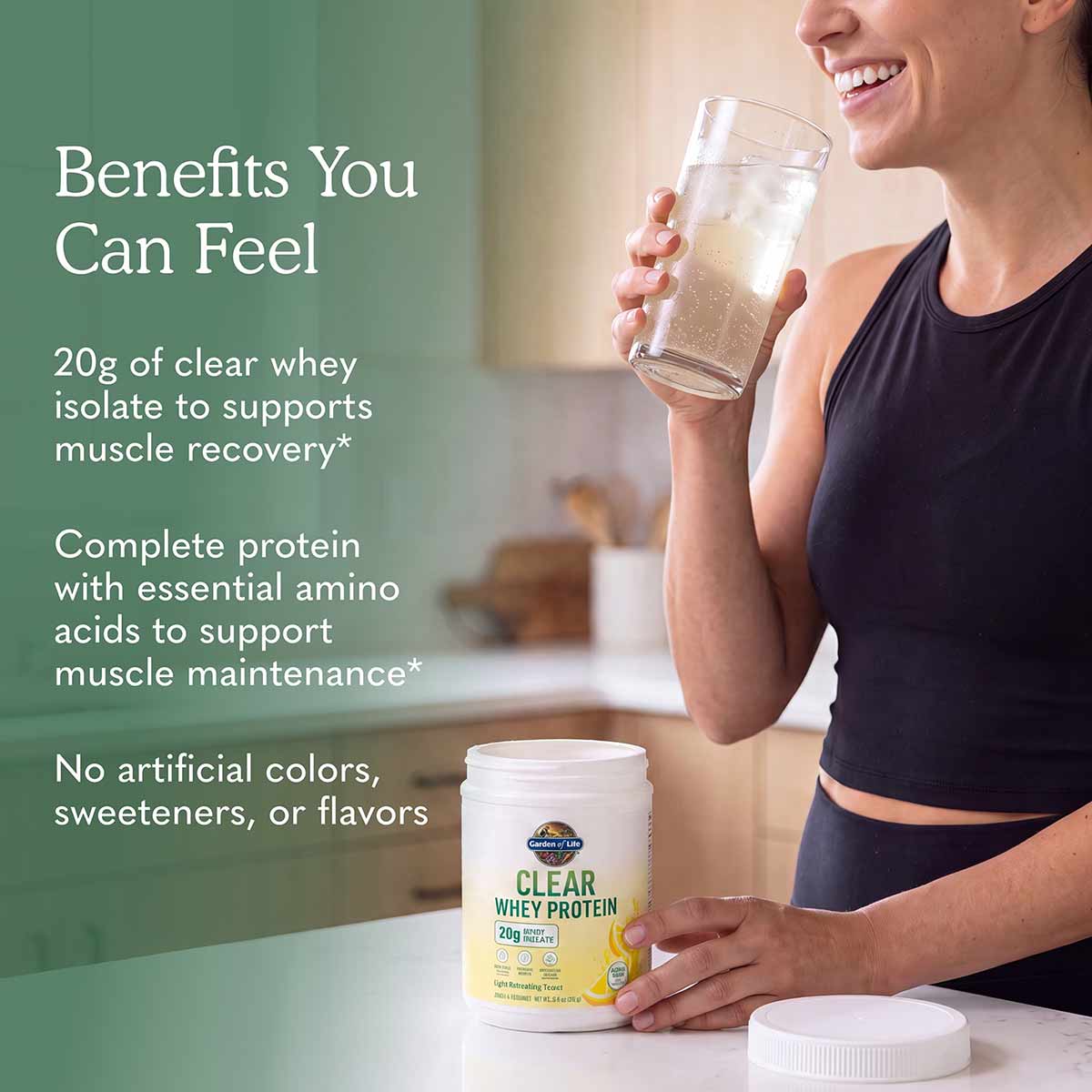 Person holding glass of clear protein drink next to Garden of Life Clear Whey Protein container on white surface.