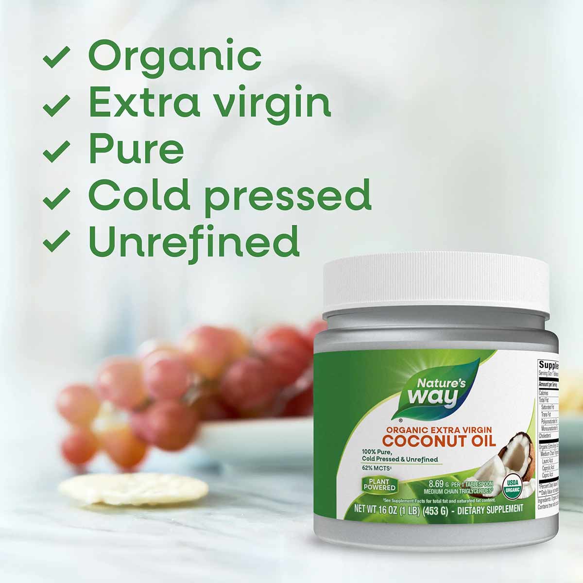 Jar of Nature's Way organic extra virgin coconut oil with white lid, 16 oz size, displayed with red apples in background.