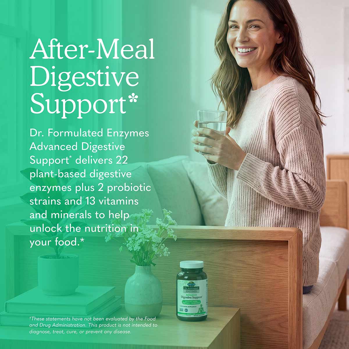 A smiling woman in a pink knit sweater holds a glass of water beside a supplement bottle on a wooden side table.
