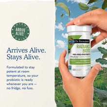 Hand holding white and green Dr. Formulated Radiance Biotic supplement bottle with 60 vegetarian capsules against outdoor bac