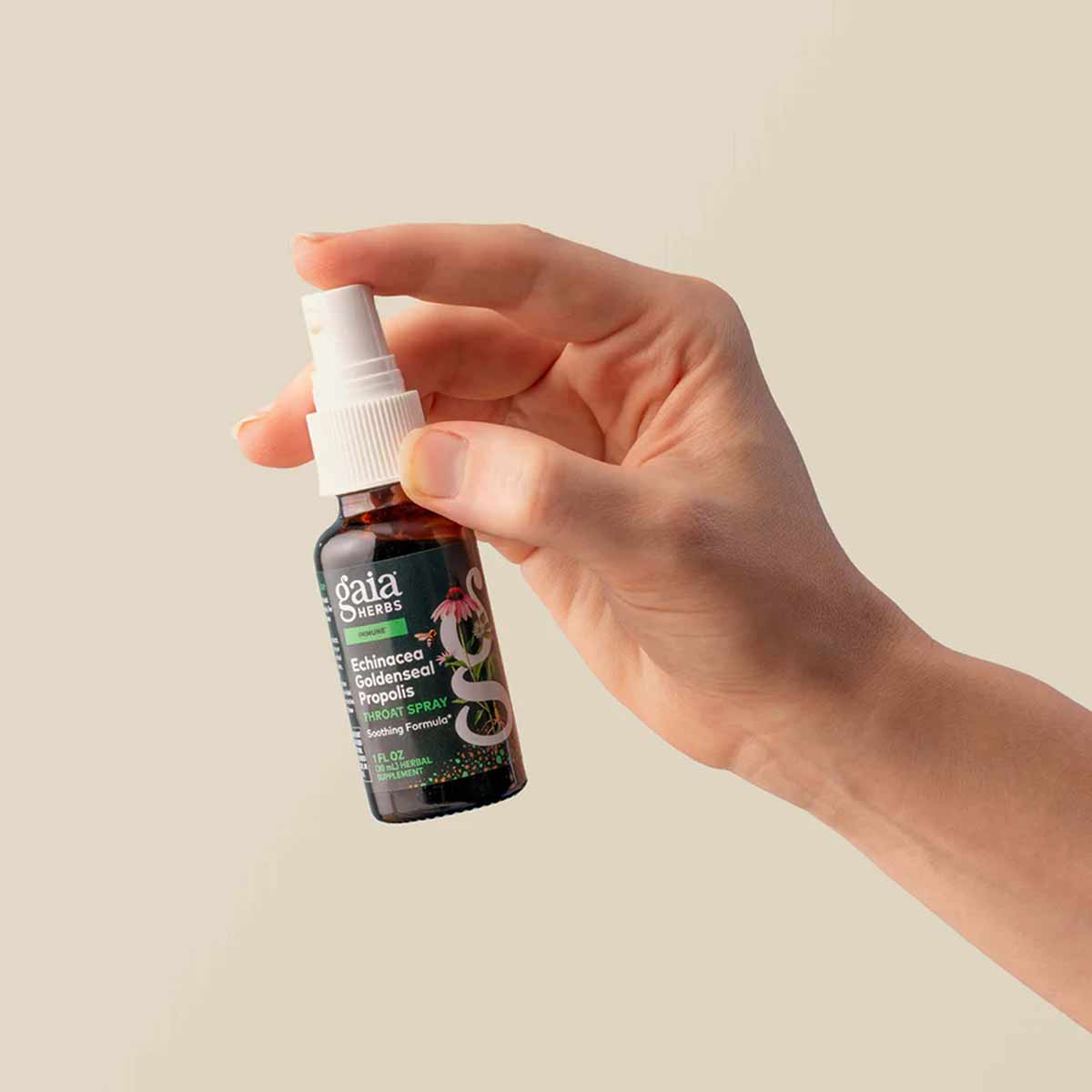 Gaia Herbs dark glass spray bottle with white pump top held in hand against neutral background.