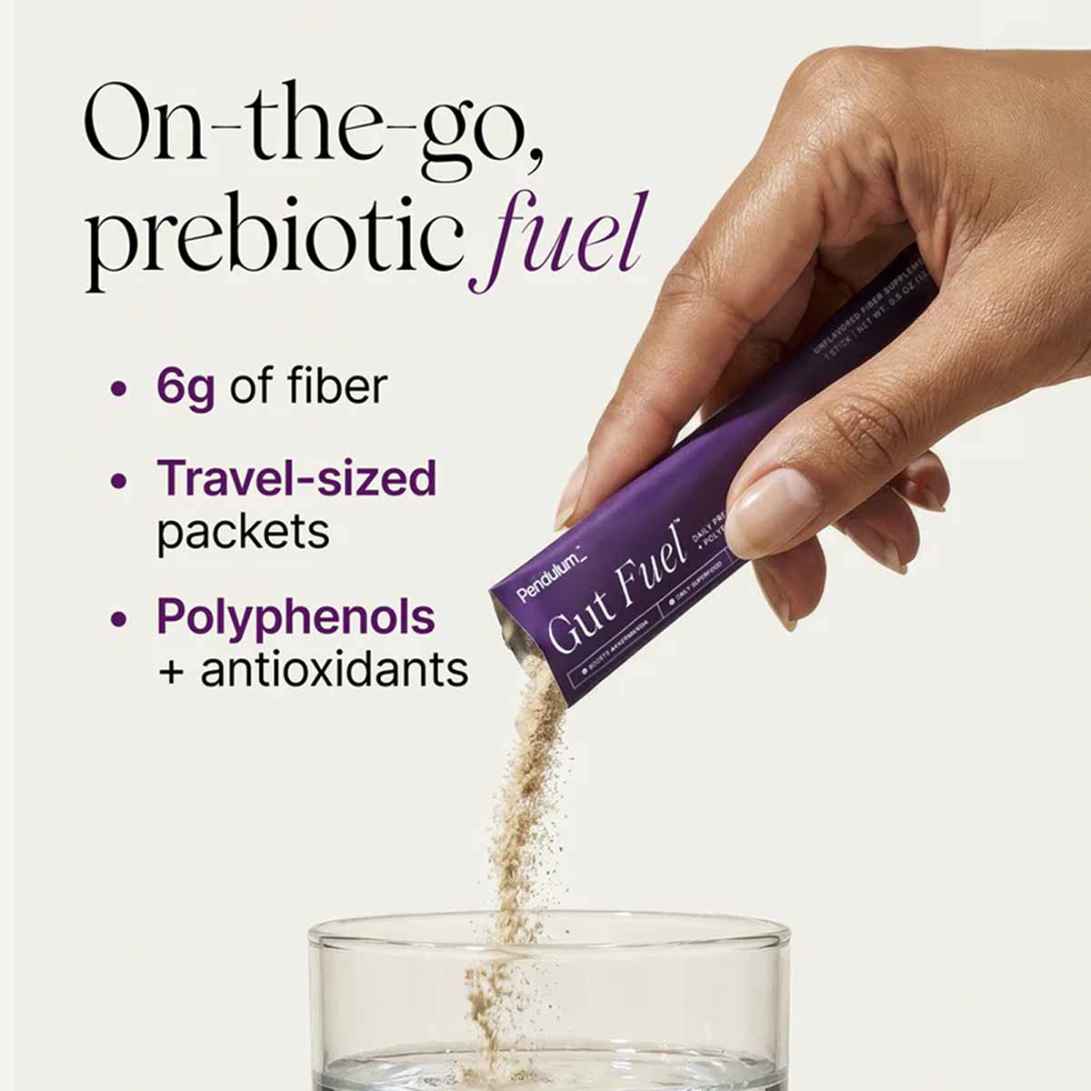 Hand pouring purple Pendulum Gut Fuel packet contents into a glass of water.
