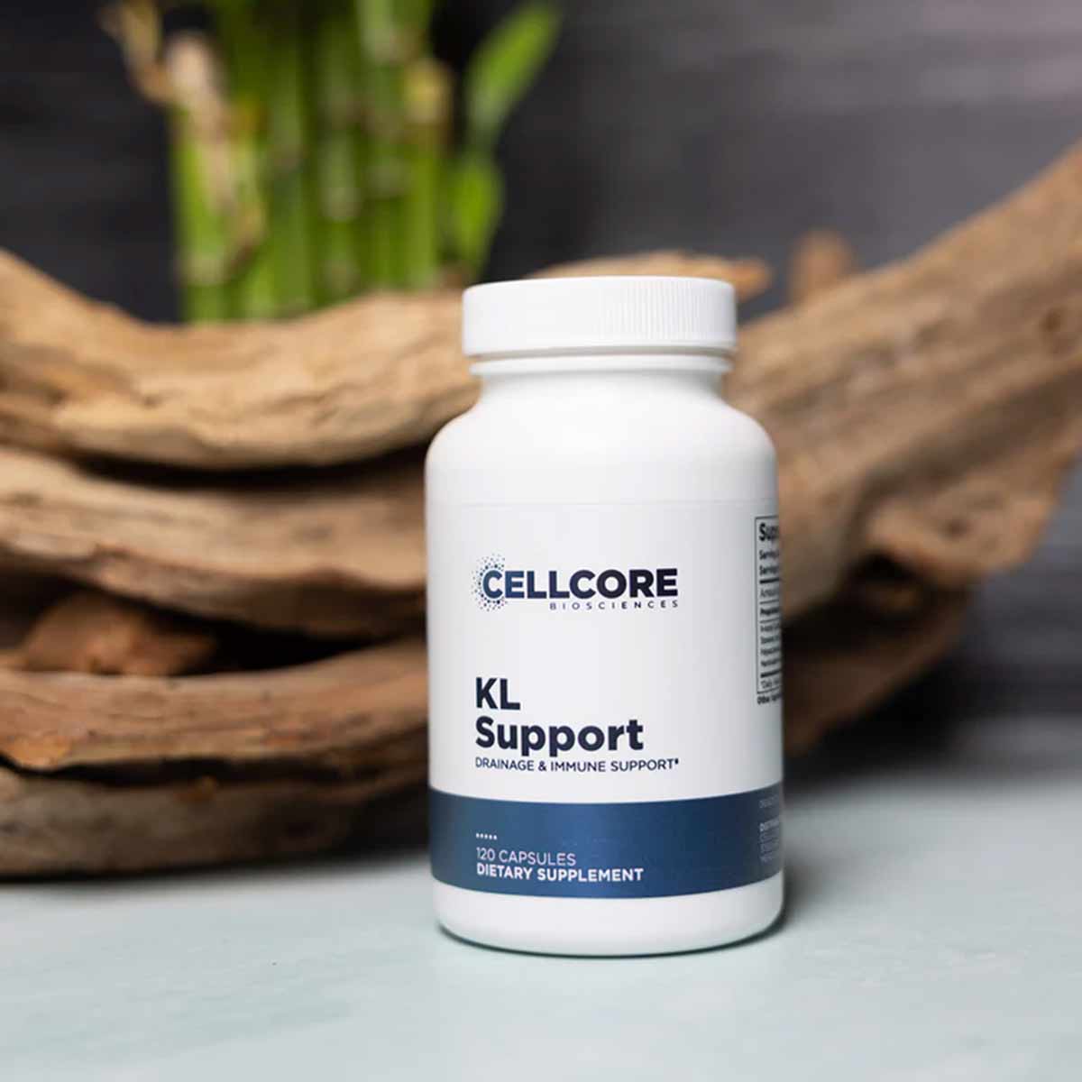 White bottle labeled KL Support by CellCore containing 120 capsules, displayed with wood and green plant styling.