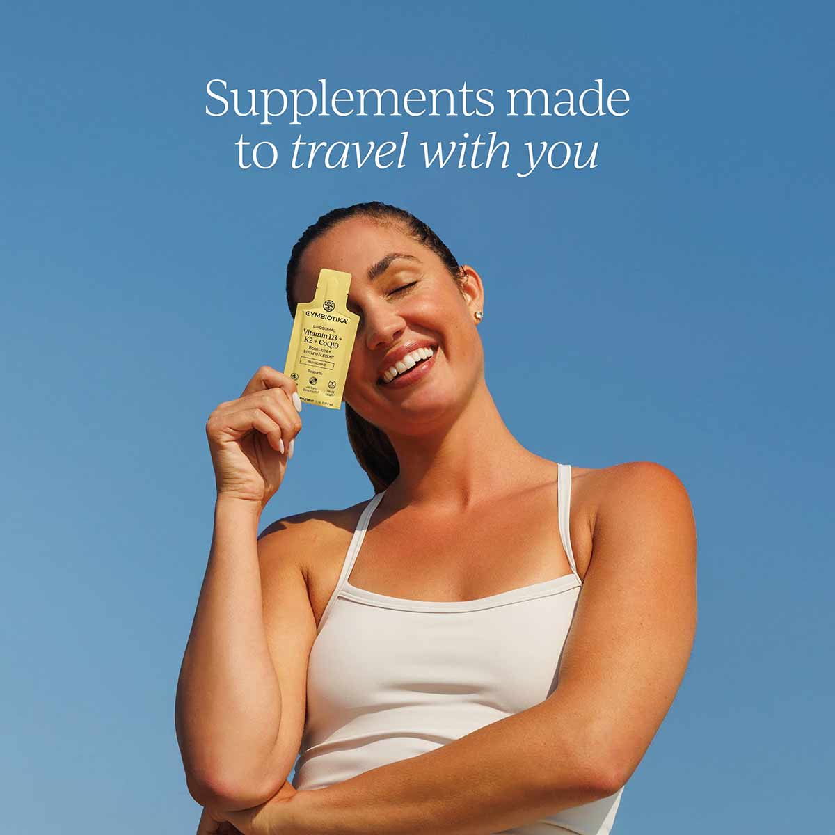 Yellow Cymbiotika supplement bottle held by person against blue background.