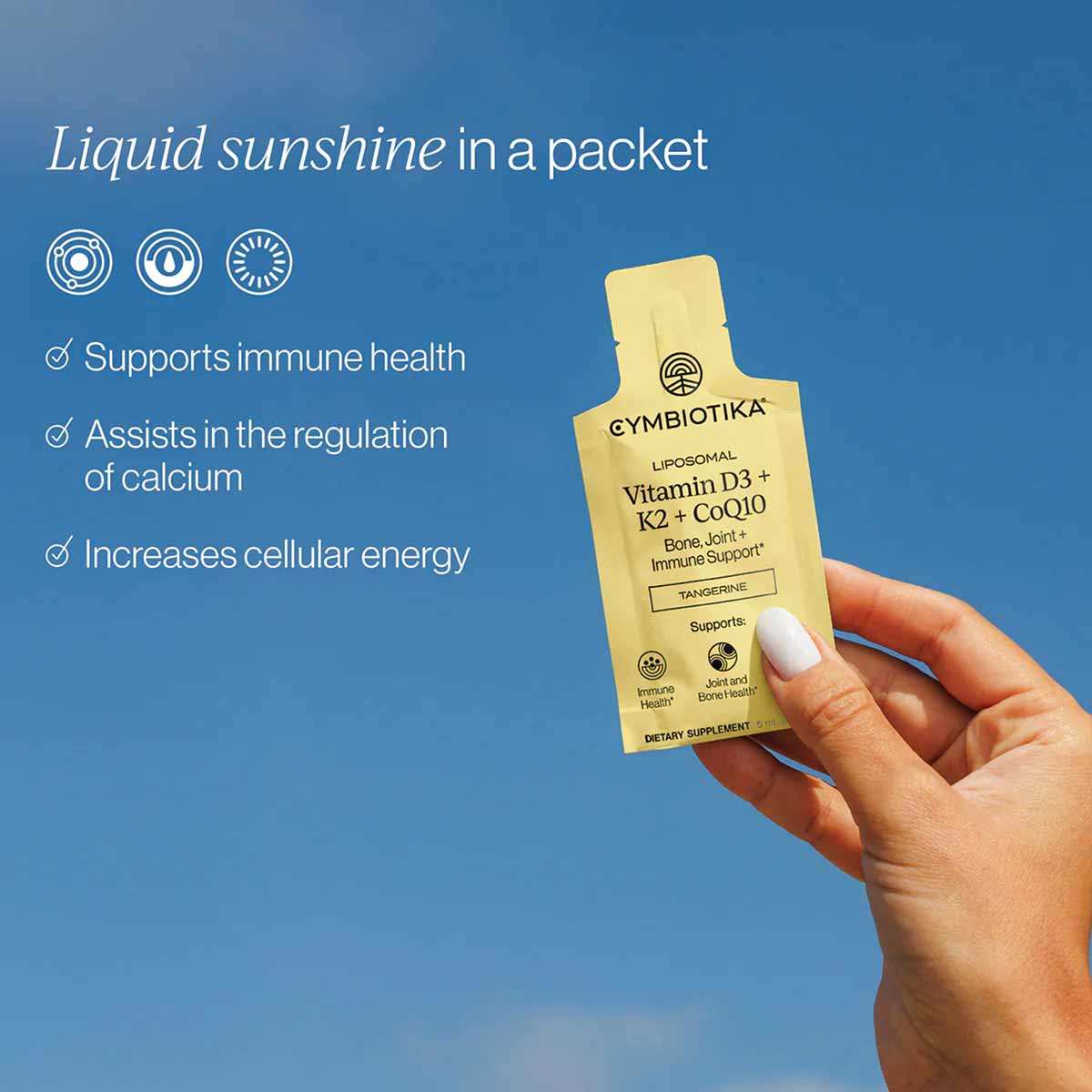 Hand holding a yellow Cymbiotika liposomal Vitamin D3+K2+CoQ10 supplement packet against a blue background.