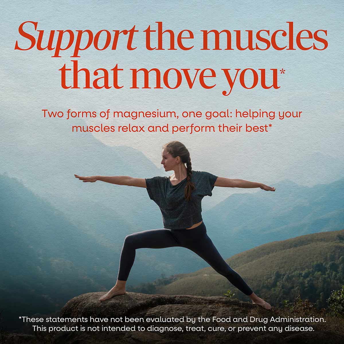 Woman in yoga pose on mountain overlook wearing dark athletic wear with arms extended.