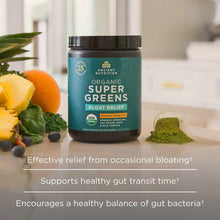 Dark jar of Ancient Nutrition Organic Super Greens Bloat Relief powder surrounded by pineapple, orange, blueberries, and gree