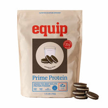 A tan Equip Prime Protein pouch labeled Cookies & Cream beef isolate protein powder stands beside a small stack of sandwich cookies.