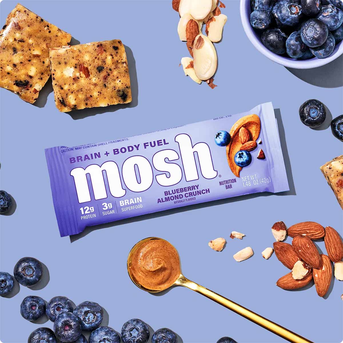 MOSH Blueberry Almond Crunch protein bar with 12g protein surrounded by blueberries, almonds, and apple slices on blue backgr