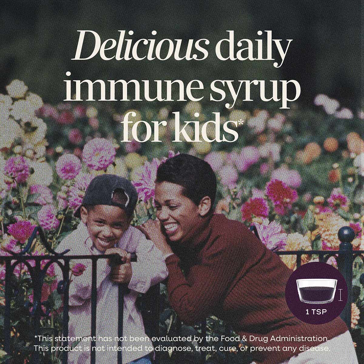 Purple-dark elderberry syrup bottle with "1 TSP" dosage indicator, displayed against a background of colorful flowers with tw