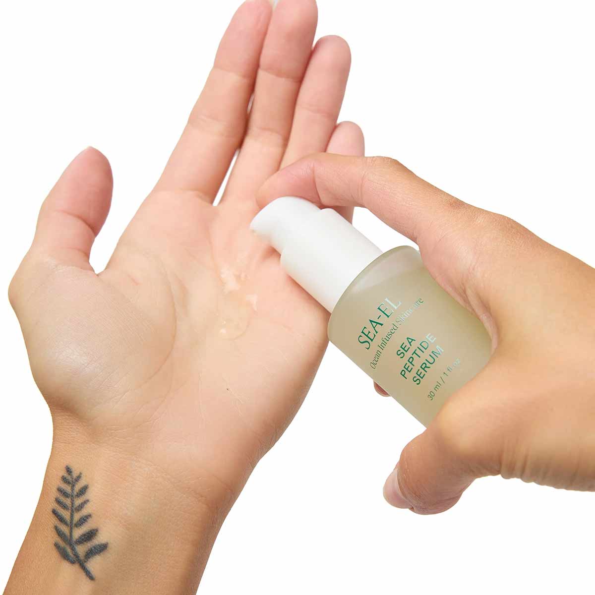 A hand pumps clear serum from a frosted green Sea-El bottle with a white pump onto an open palm.