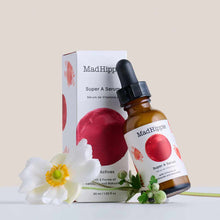 Amber glass dropper bottle of Mad Hippie Super A Serum displayed with white box packaging, white flower, and green foliage.