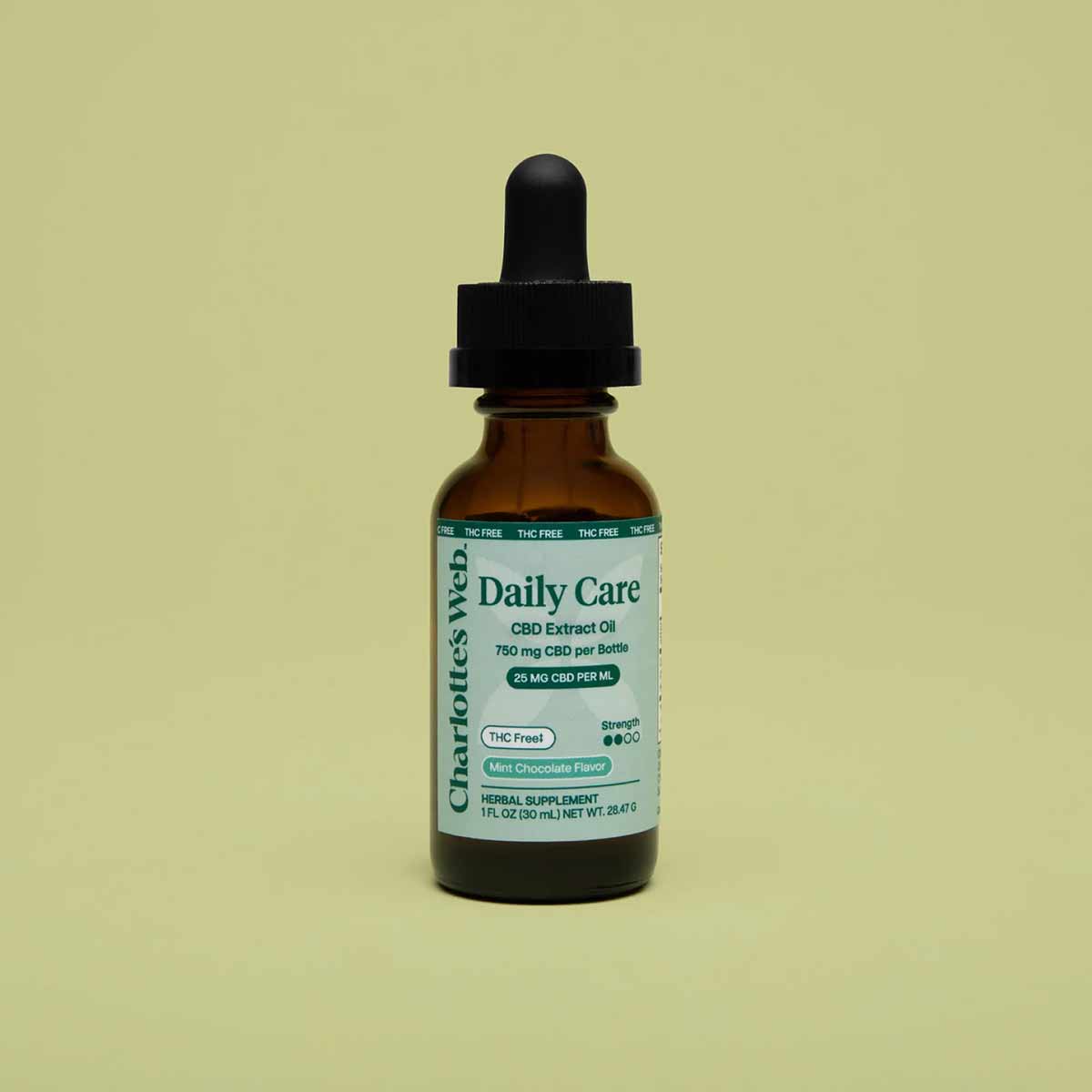 Brown glass bottle with black dropper cap labeled "Charlotte's Web Daily Care CBD Extract Oil" on pale yellow background.