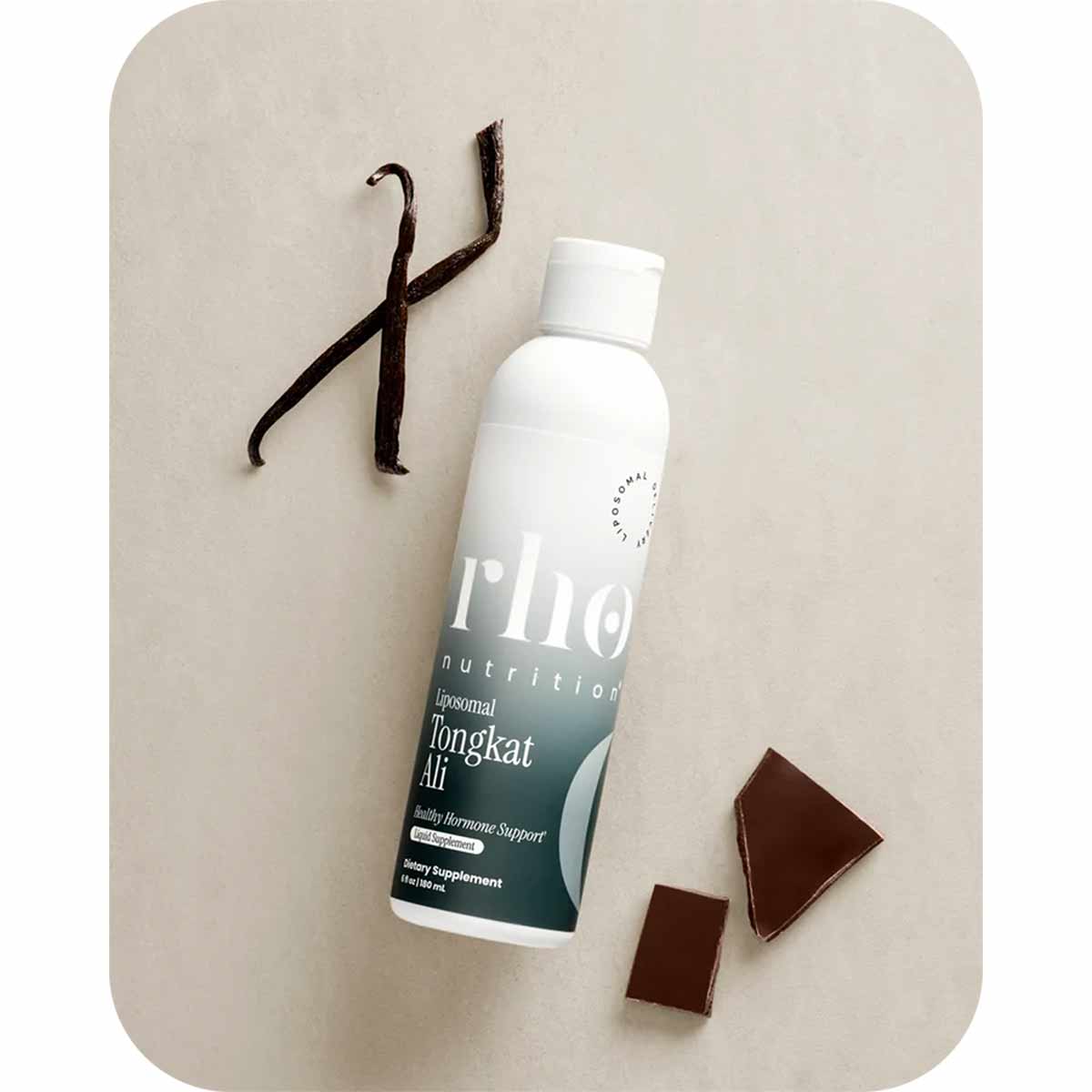White bottle of Rho Nutrition Tongkat Ali supplement with dark label, displayed next to vanilla pods and dark chocolate piece