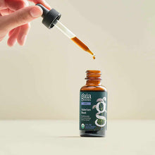 Hand holding dropper above brown glass Gaia Herbs Valerian Root bottle with dark label.