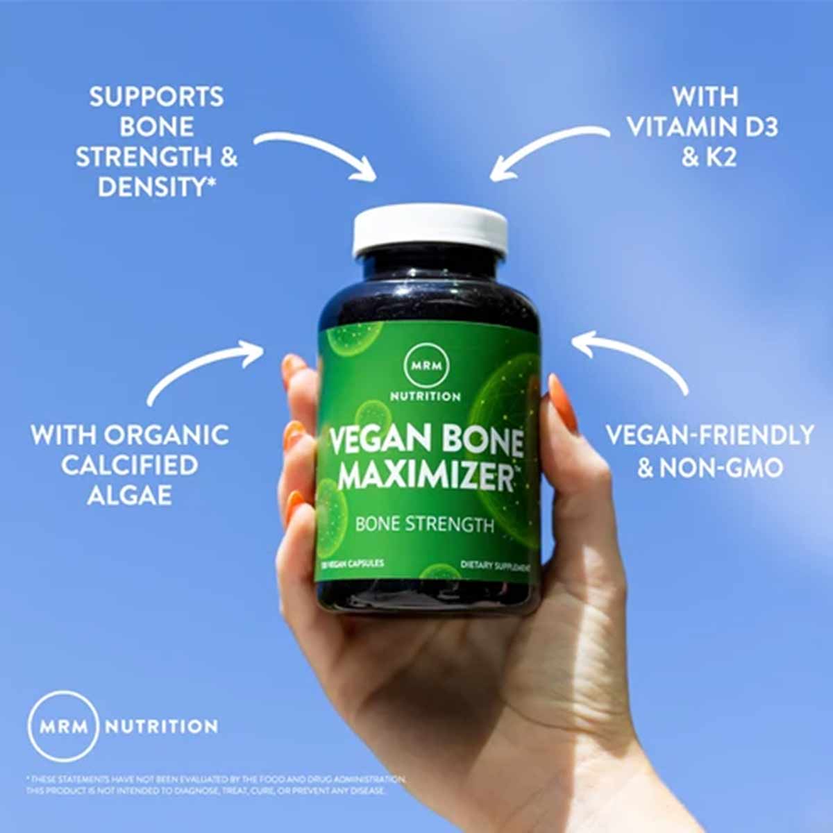 Hand holding dark blue bottle with green label reading "Vegan Bone Maximizer" by MRM Nutrition against blue background with f