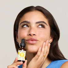 Mad Hippie Vitamin C Serum 1.02 oz bottle with dropper held by person applying product to face.