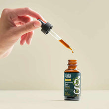 Hand holding dropper over amber glass bottle labeled Gaia Herbs Wormwood Black Walnut Supreme liquid extract.